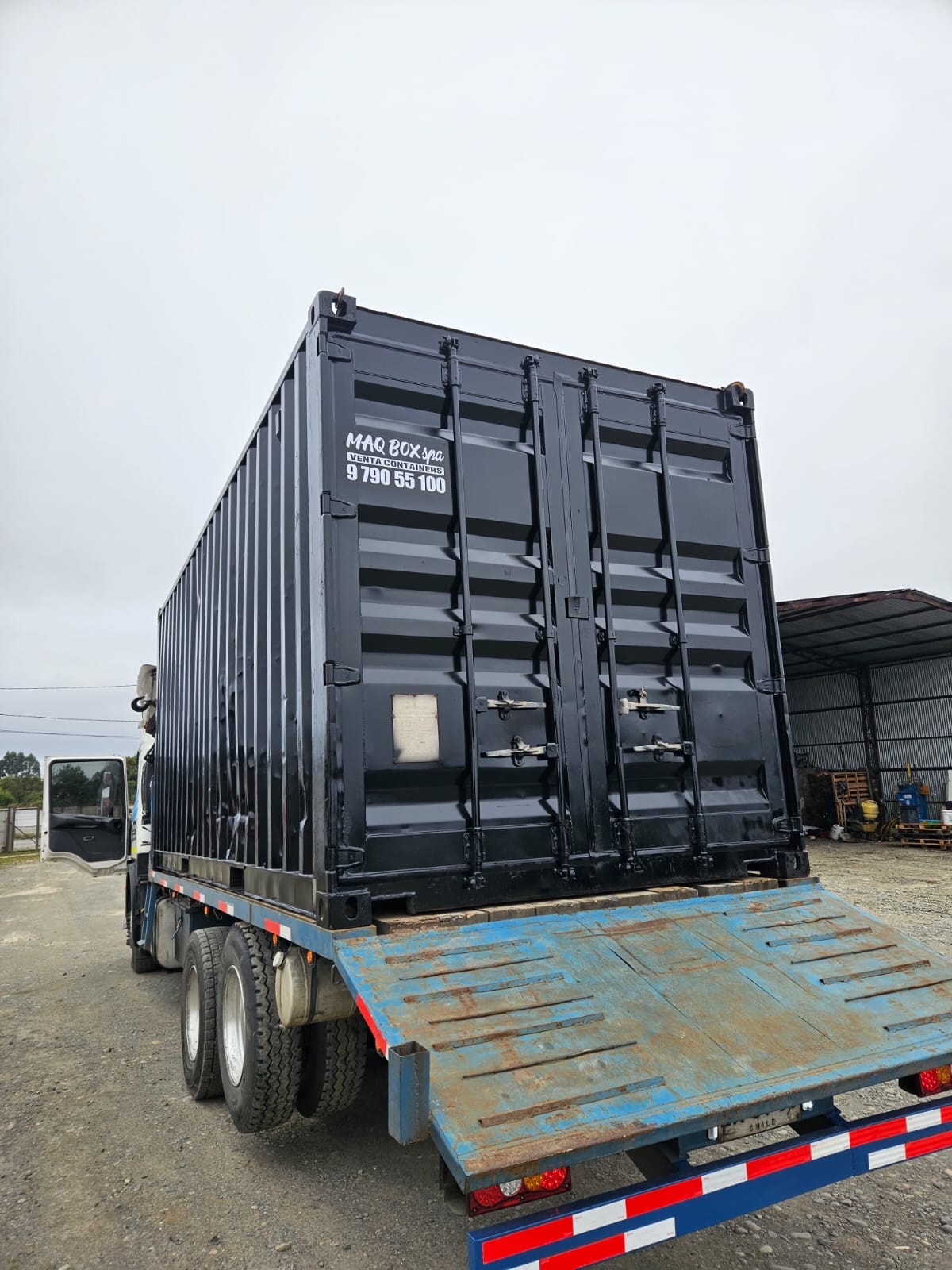 Traslado de container negro sobre camión rampla